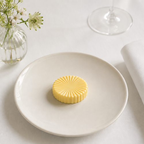 Butter Soleil Mold presentation on a minimalist fine dining table with white tablecloth and floral centerpiece