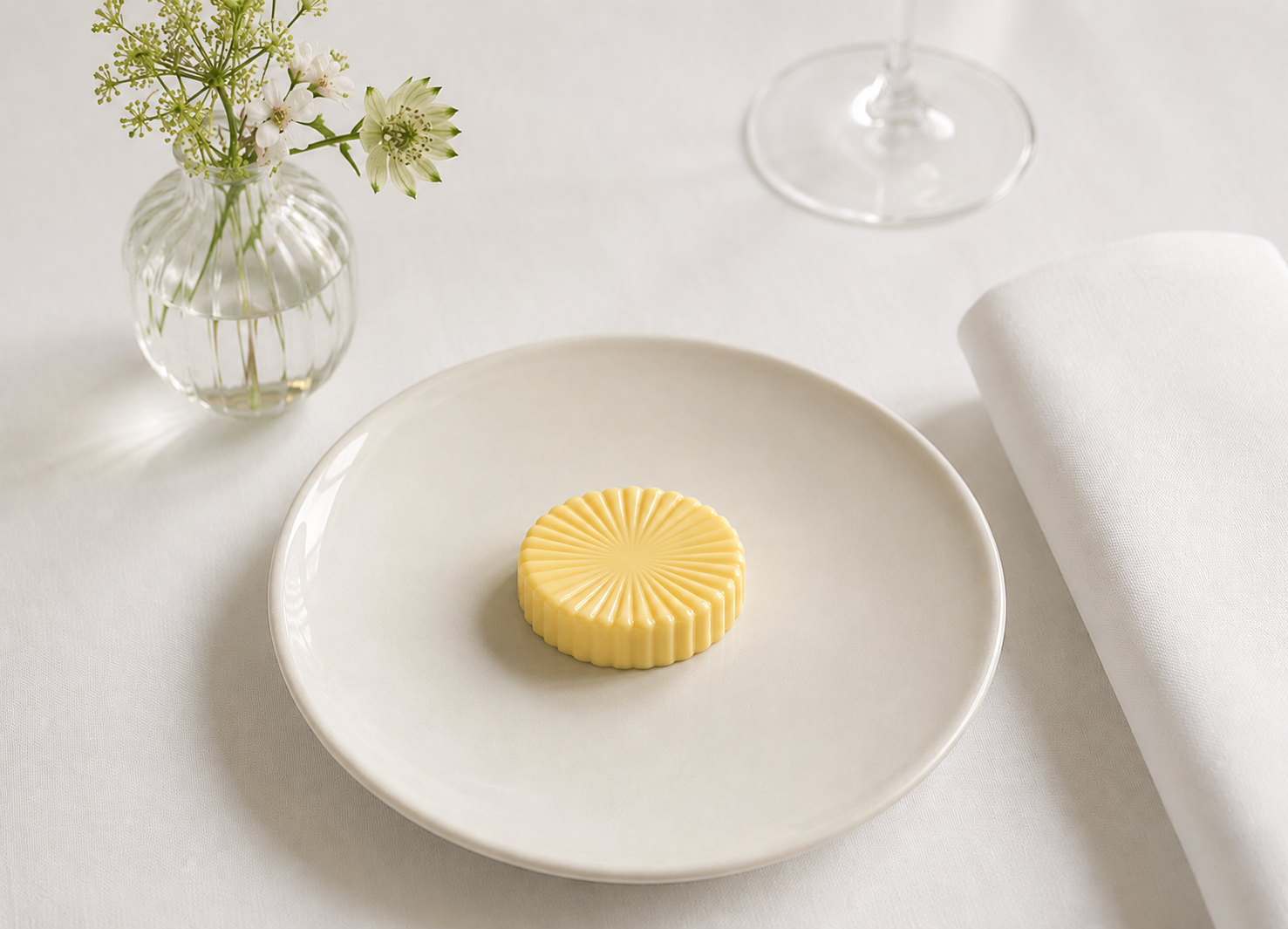 Butter Soleil Mold presentation on a minimalist fine dining table with white tablecloth and floral centerpiece